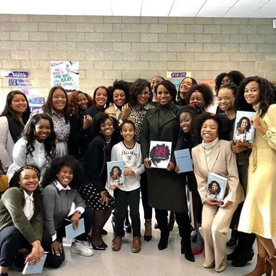 A group photo of kids and women holding a book